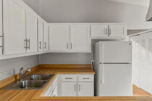 a kitchen with white cabinets and refrigerator