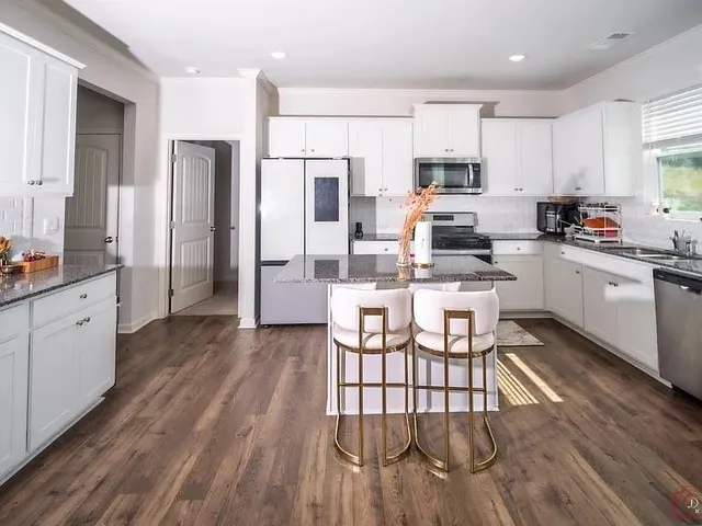 a kitchen with stainless steel appliances a stove a sink a refrigerator cabinets and wooden floor