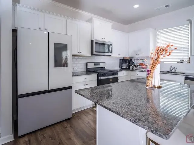 a kitchen with stainless steel appliances granite countertop a refrigerator a stove a sink a microwave and cabinets