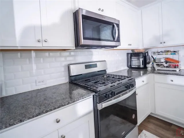 a kitchen with granite countertop white cabinets stainless steel appliances and a sink