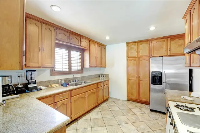 a kitchen with stainless steel appliances granite countertop a stove a sink dishwasher and a microwave oven with large cabinets