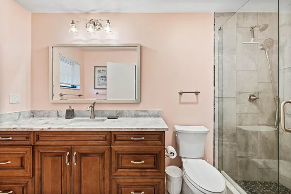 a bathroom with a granite countertop toilet sink and mirror