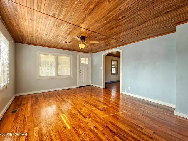 a view of an empty room with window and wooden floor