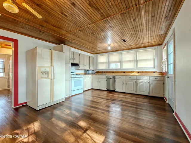 a view of a kitchen with a sink and dishwasher a refrigerator with wooden floor