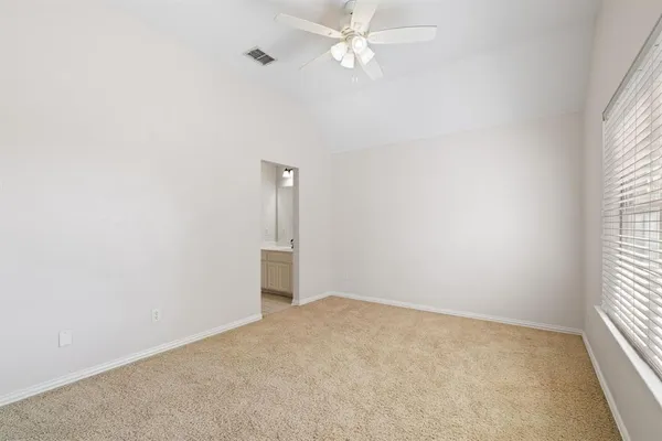 an empty room with a window and ceiling fan