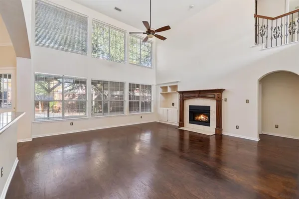a view of an empty room with a fireplace and wooden floor