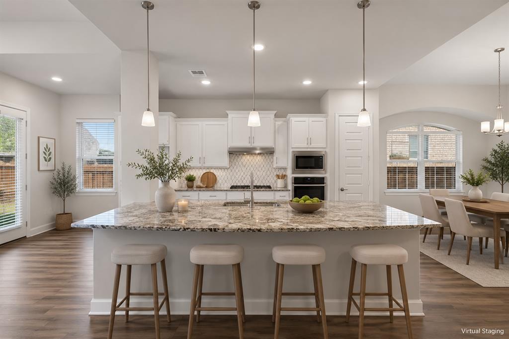 2813 Trinity Ridge Street Mansfield, TX 76063 - Photo 3 of 27 Kitchen featuring a spacious island with a speckled countertop, white cabinetry, built-in double ovens, and a tile backsplash