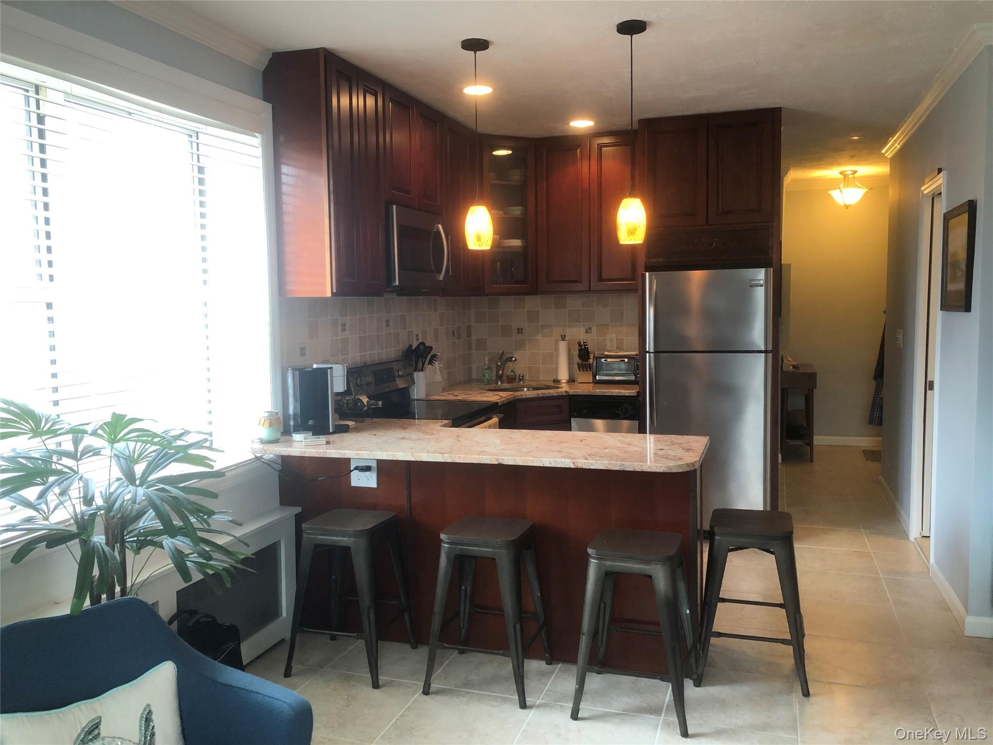 855 East Broadway, Unit LD Long Beach, NY 11561 - Photo 4 of 9 a kitchen with kitchen island granite countertop a sink a center island and stainless steel appliances