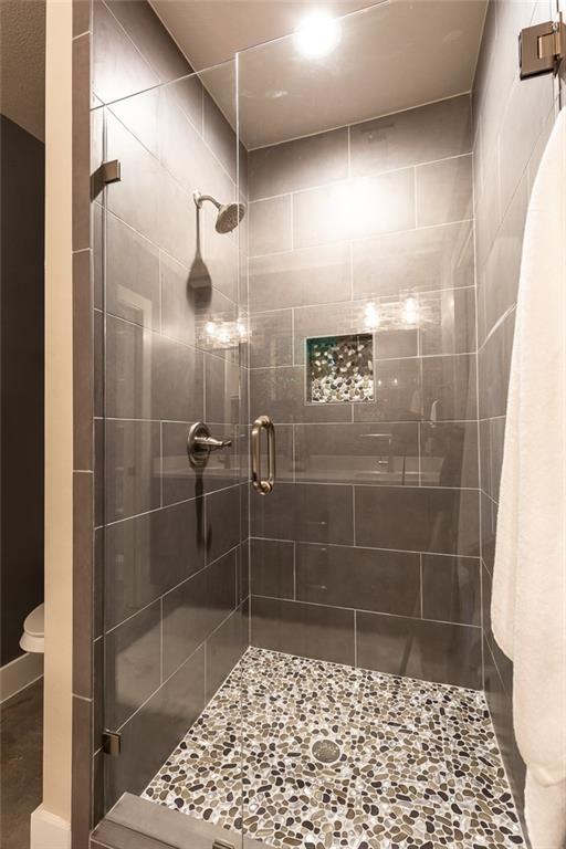 1142 Eleanor Street, Unit 2 Austin, TX 78721 - Photo 18 of 24 A frameless glass enclosure complements the dark tiled walls and pebbled floor of this shower.
