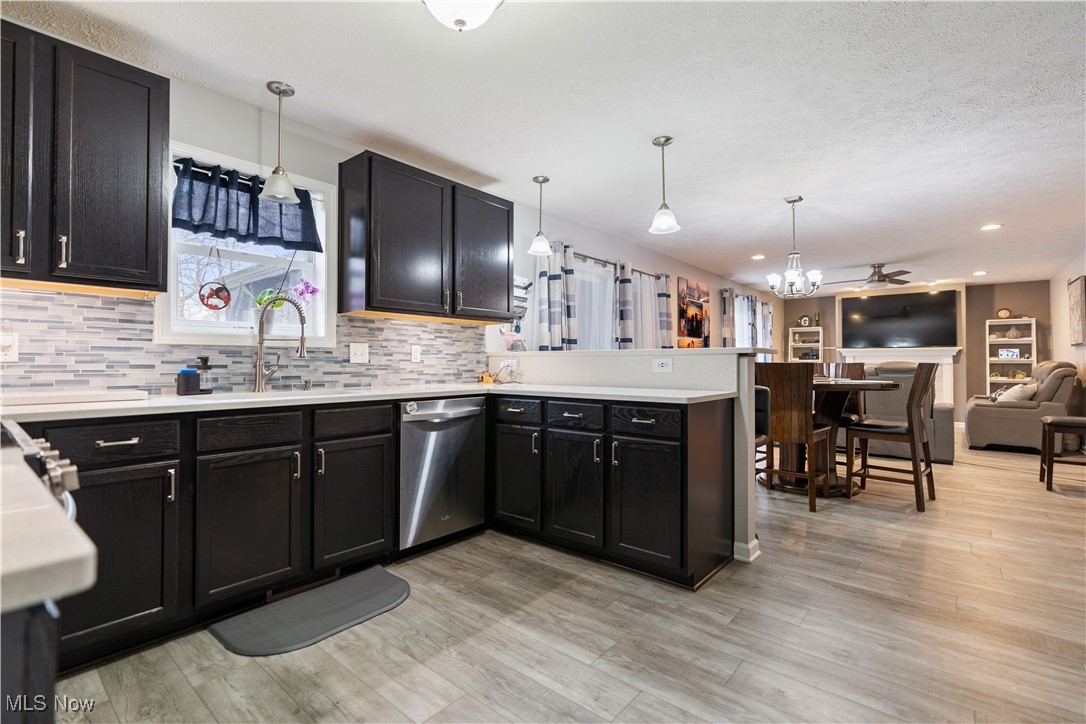 2542 Call Road Stow, OH 44224 - Photo 10 of 47 Kitchen featuring kitchen peninsula, stainless steel dishwasher, hanging light fixtures, light hardwood / wood-style flooring, and decorative backsplash