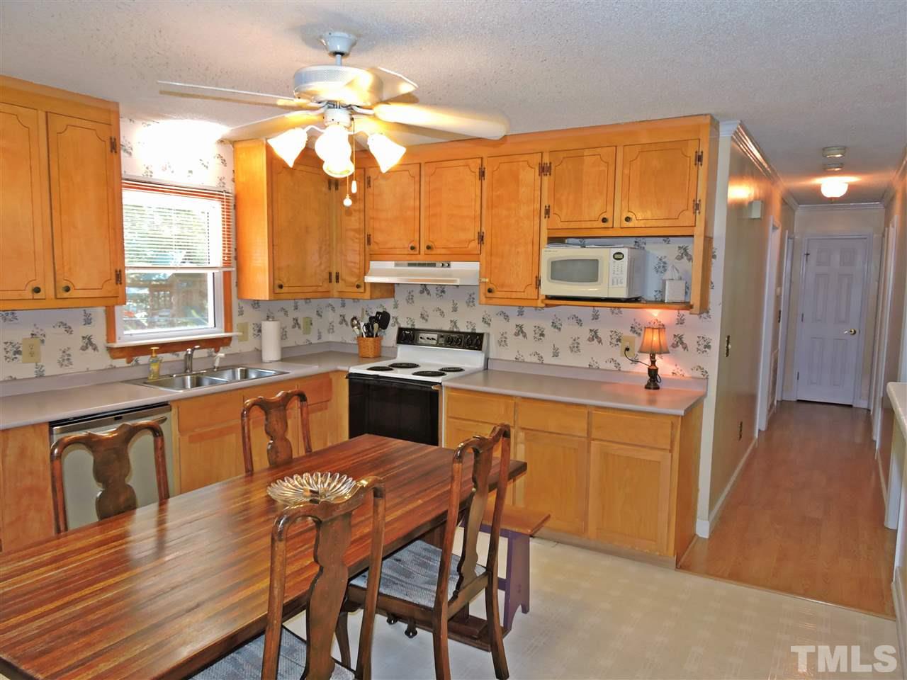 6602 Whitt Road Durham, NC 27712 - Photo 3 of 15 a kitchen with stainless steel appliances granite countertop wooden cabinets a stove a sink a dining table and chairs