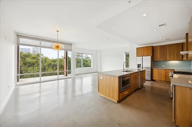 a living room with stainless steel appliances kitchen island granite countertop a stove and a large window