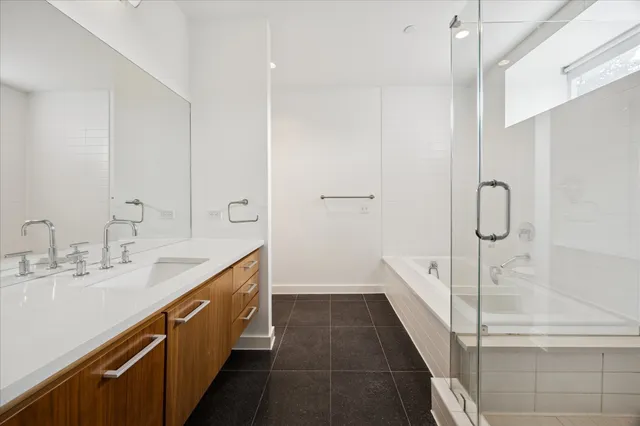 a spacious bathroom with a double vanity sink a large mirror and shower