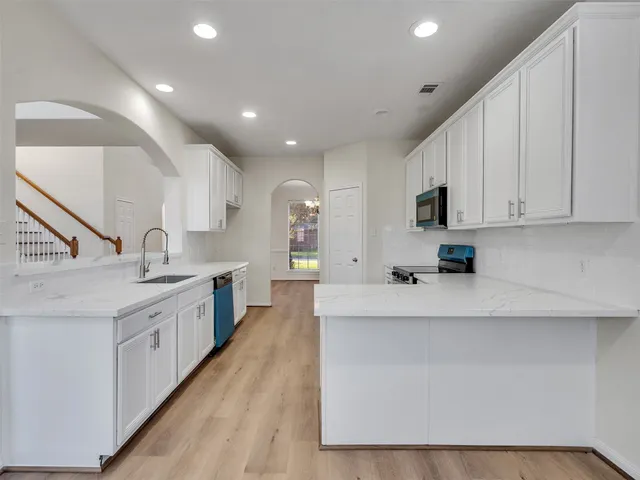a large kitchen with stainless steel appliances a sink a stove and cabinets