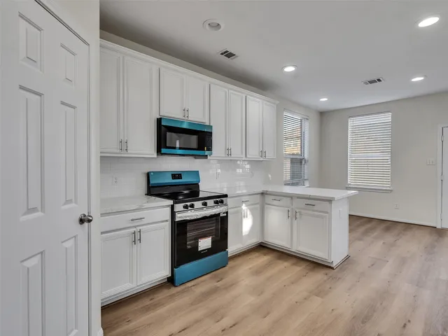 a kitchen with granite countertop white cabinets and stainless steel appliances