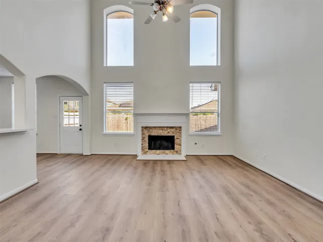 an empty room with windows a fireplace and wooden floor
