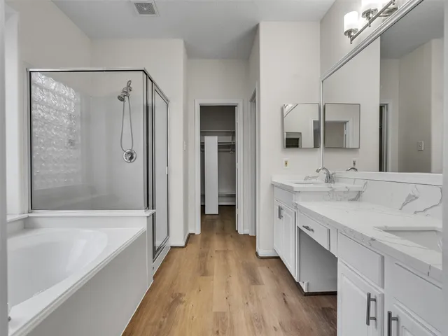 a spacious bathroom with a double vanity sink a mirror and a bathtub