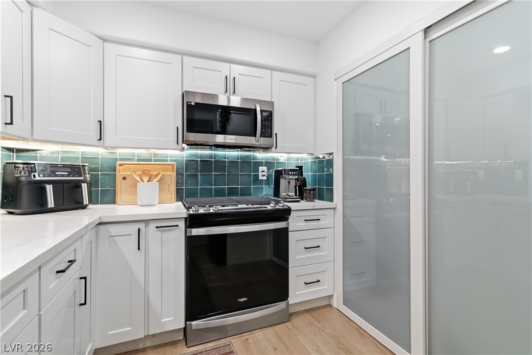 7950 West Flamingo Road, Unit 1180 Las Vegas, NV 89147 - Photo 14 of 26 A well-equipped kitchen showcasing sleek appliances and a stylish tiled backsplash.