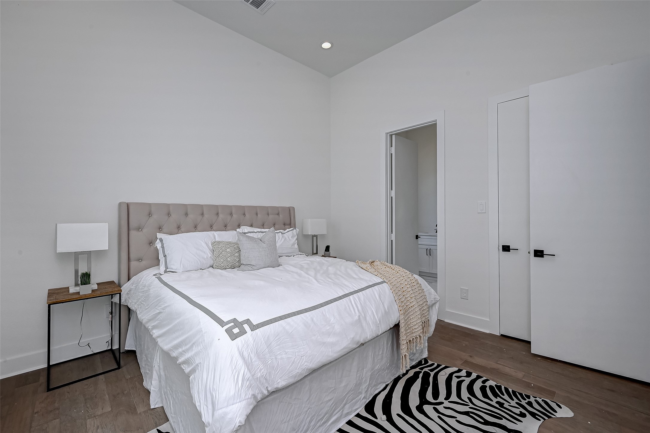 6129 West Montgomery Road Houston, TX 77091 - Photo 13 of 17 Another angle of the serene primary suite shows off modern doors, tall ceilings, and private en-suite access. Clean lines and neutral tones create a spa-like sense of calm.