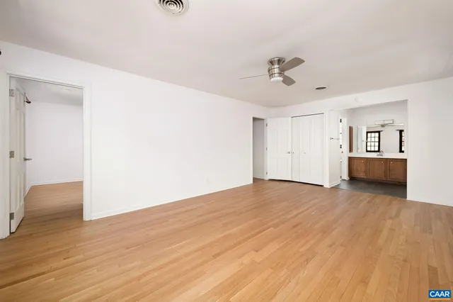 an empty room with wooden floor and ceiling fan