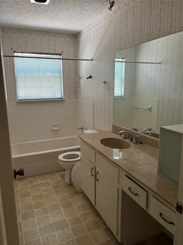 a bathroom with a granite countertop sink a toilet and a mirror