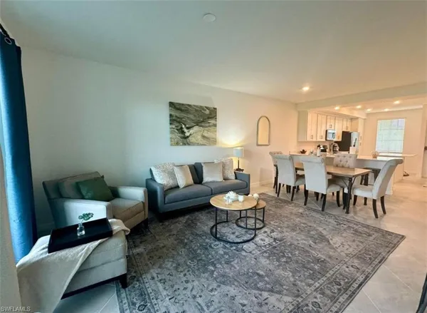 a living room with furniture and a dining table with wooden floor