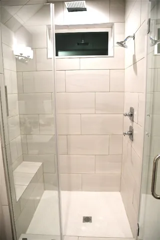 a bathroom with a shower and a tiled wall