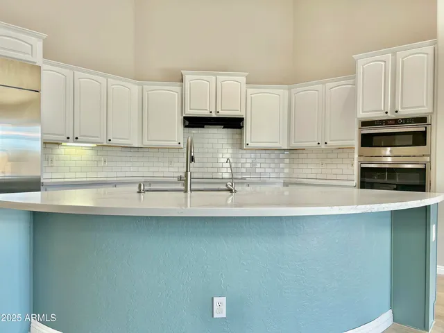a kitchen with stainless steel appliances granite countertop a sink a stove and white cabinets