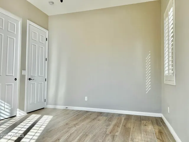 a view of an empty room with wooden floor and a window