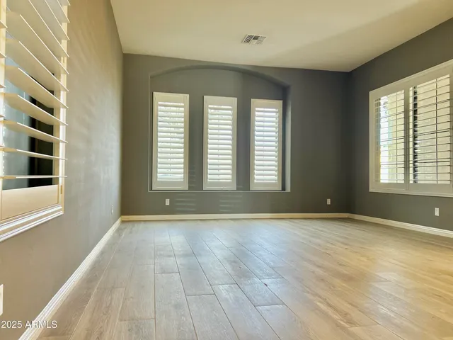 a view of an empty room with a window and wooden floor