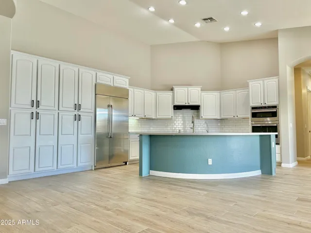 a view of kitchen with stainless steel appliances wooden floor and living room view
