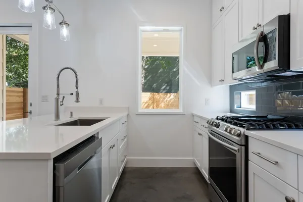 a kitchen with stainless steel appliances granite countertop a stove a sink and a microwave
