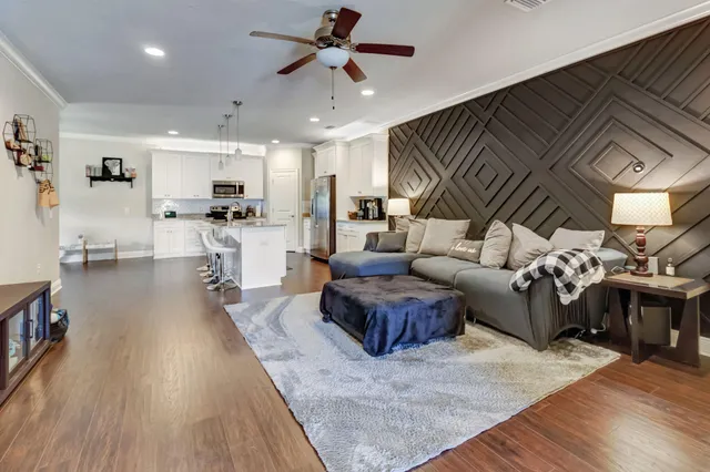 a living room with furniture kitchen view and a wooden floor