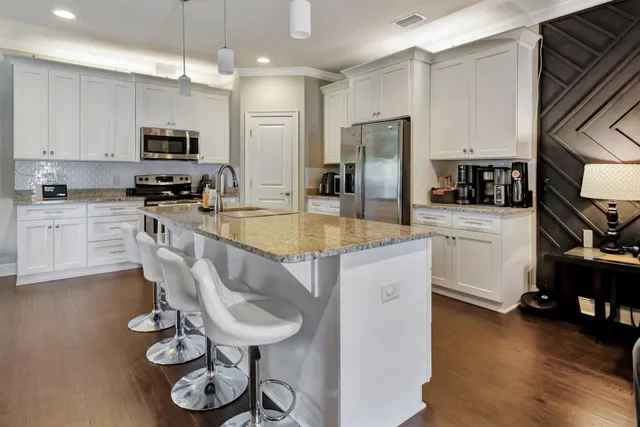 a kitchen with granite countertop a sink a stove a refrigerator cabinets and wooden floor