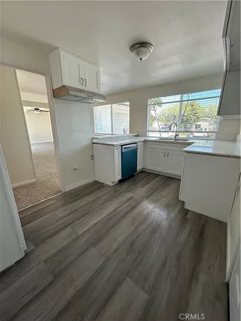 a kitchen with wooden floors and white cabinets