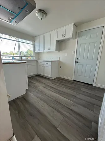 a kitchen with granite countertop white cabinets and wooden floor