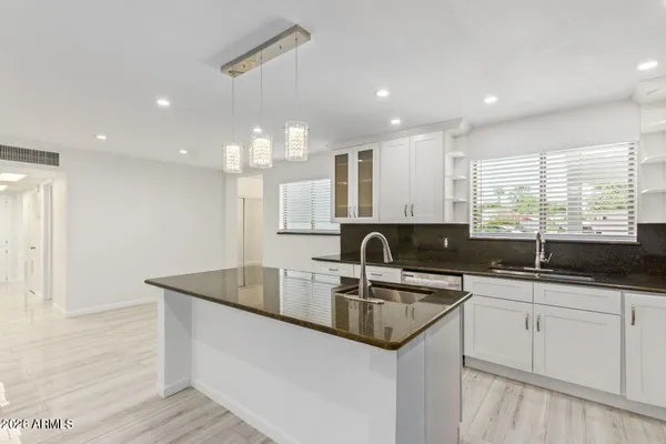 a kitchen with granite countertop a sink and white cabinets