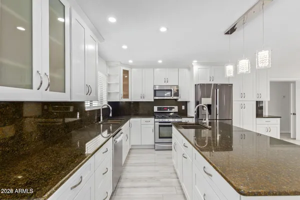 a large kitchen with stainless steel appliances granite countertop a sink a stove and a refrigerator