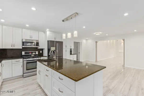 a kitchen with kitchen island granite countertop a sink a counter top stainless steel appliances and cabinets