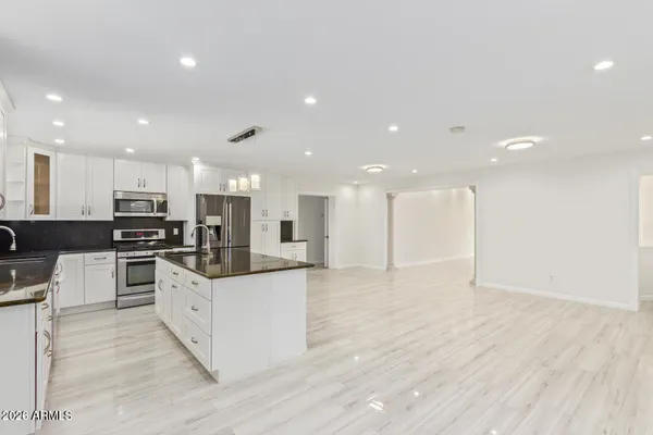 a large kitchen with stainless steel appliances kitchen island a large counter top and a stove top oven