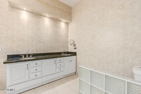a bathroom with a granite countertop sink and white cabinets