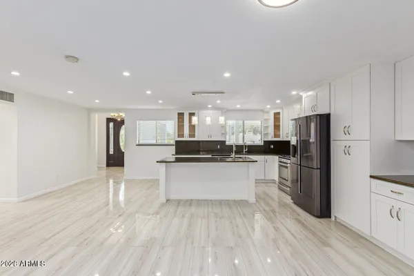 a large white kitchen with kitchen island a sink a refrigerator and a stove top oven