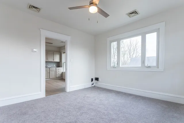 an empty room with a window and a chandelier fan