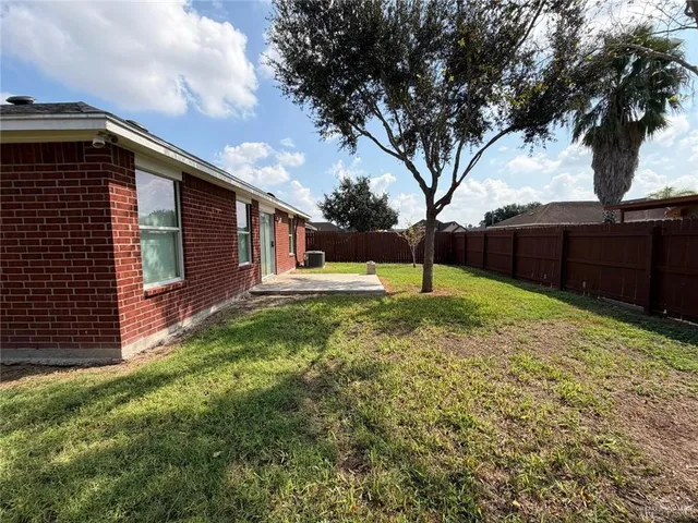 a view of a backyard with wooden fence and a large tree