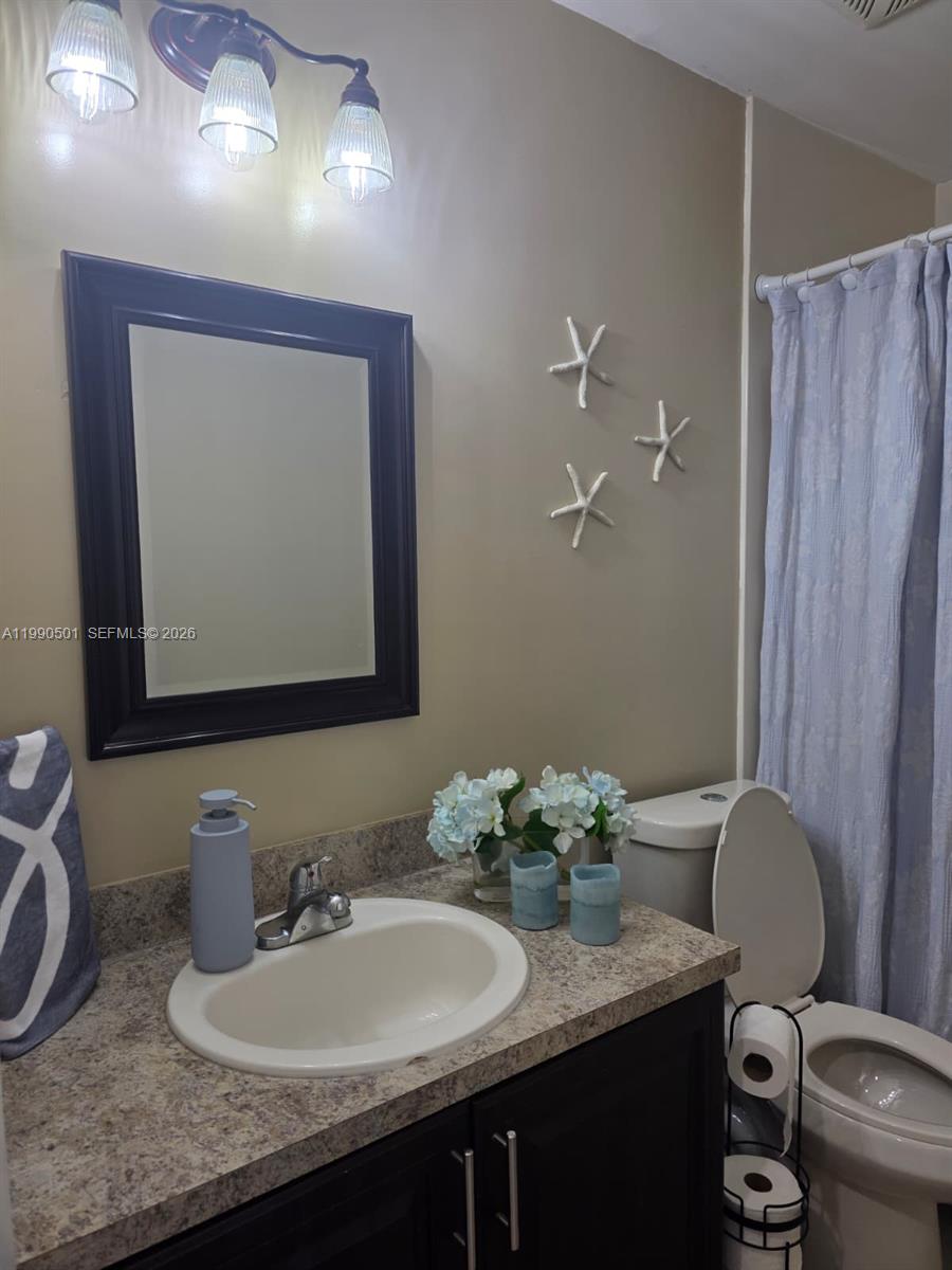 893 Southwest 120th Way Davie, FL 33325 - Photo 18 of 22 a bathroom with a granite countertop sink a toilet and mirror