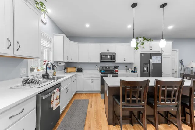 a kitchen with stainless steel appliances kitchen island granite countertop a table chairs sink and cabinets