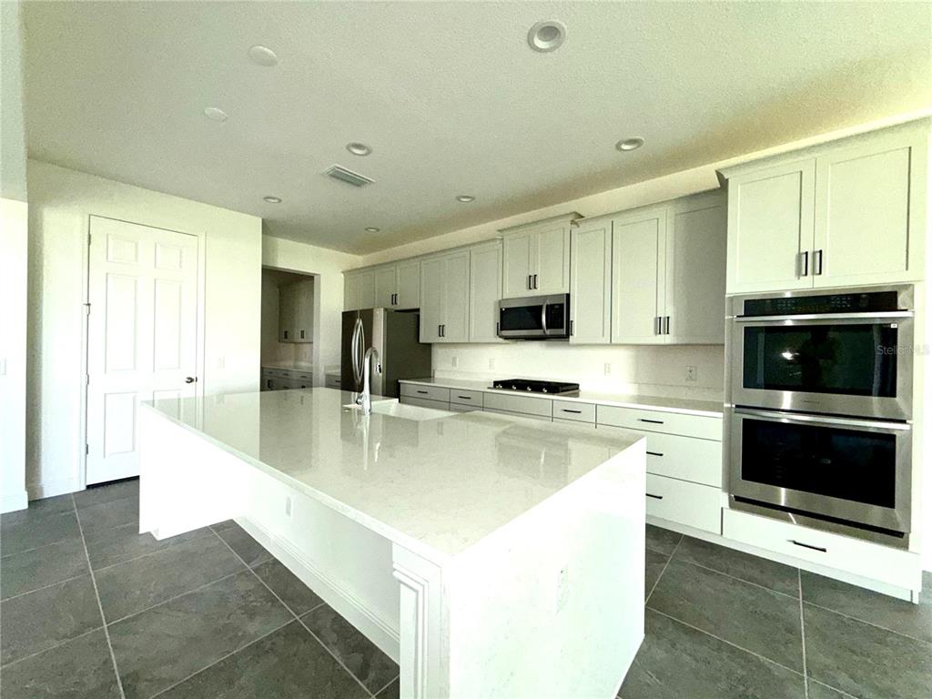 394 Switchgrass Loop Minneola, FL 34715 - Photo 12 of 26 a large kitchen with stainless steel appliances granite countertop a stove a sink and a microwave