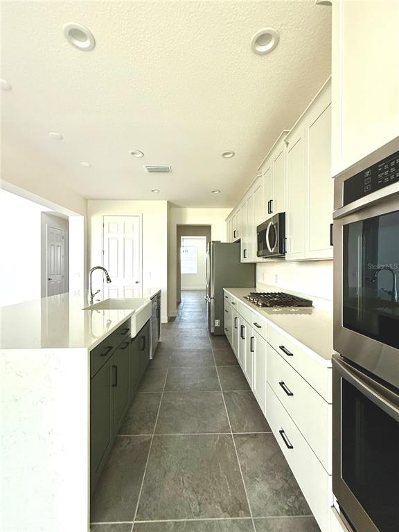 394 Switchgrass Loop Minneola, FL 34715 - Photo 13 of 26 a large kitchen with granite countertop a stove and a sink