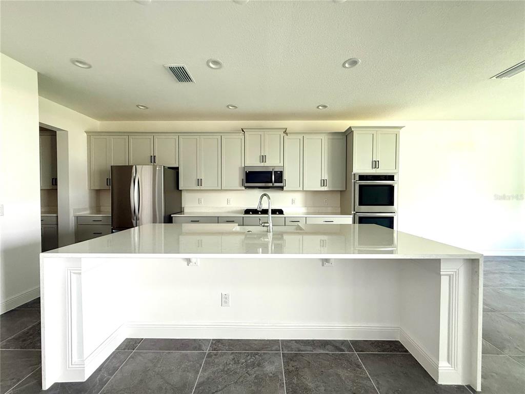 394 Switchgrass Loop Minneola, FL 34715 - Photo 4 of 26 a view of a kitchen with kitchen island a sink stainless steel appliances and cabinets