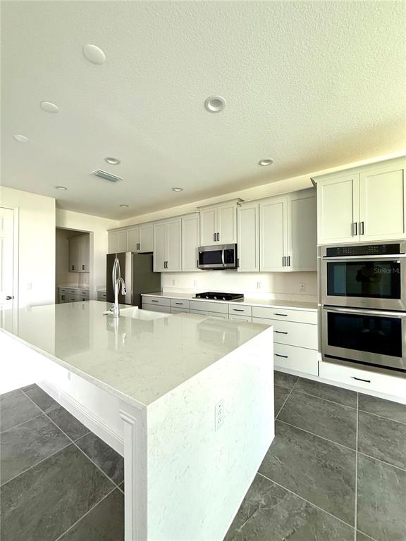 394 Switchgrass Loop Minneola, FL 34715 - Photo 8 of 26 a large kitchen with stainless steel appliances granite countertop a stove a sink and a microwave